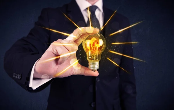 Business person holding an electric light bulb — Stock Photo, Image