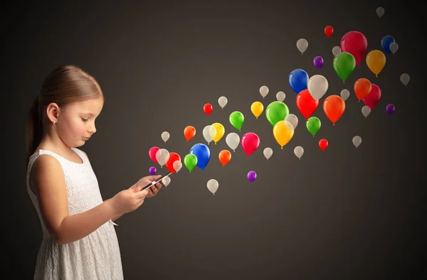 Menina segurando comprimido com balões coloridos ao redor — Fotografia de Stock