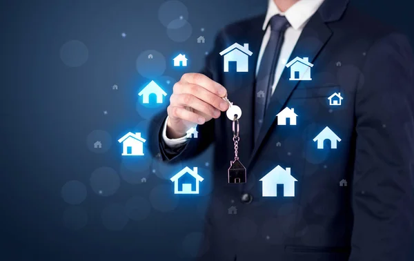Empresário segurando chaves com casas ao redor — Fotografia de Stock
