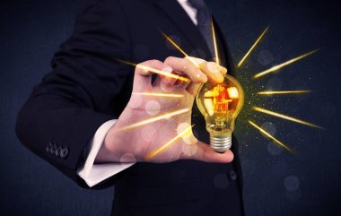 bir elektrik ampulü tutan iş kişi