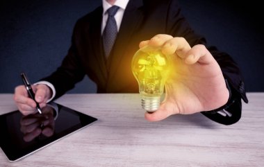 parlak sarı ampul tutan takım elbiseli adam