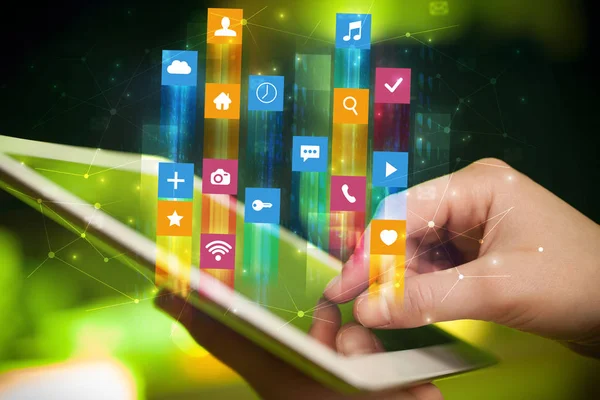 Hand using tablet with application icons flying around — Stock Photo, Image