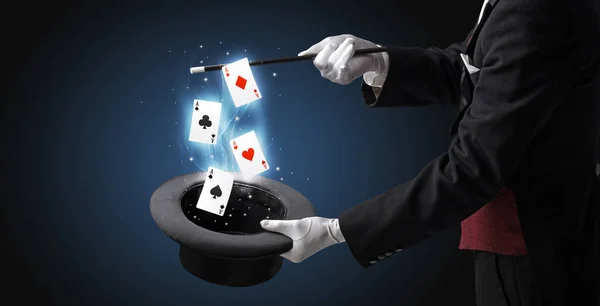 Magician making trick with wand and playing cards — Stock Photo, Image