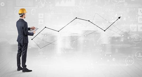 Ingenieur, der einen Plan hält und mit Diagrammen, Diagrammen und Berichten im Hintergrund steht — Stockfoto