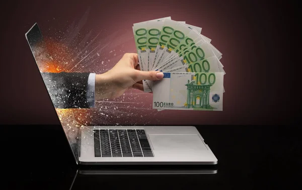 Hand with cash coming out of a laptop