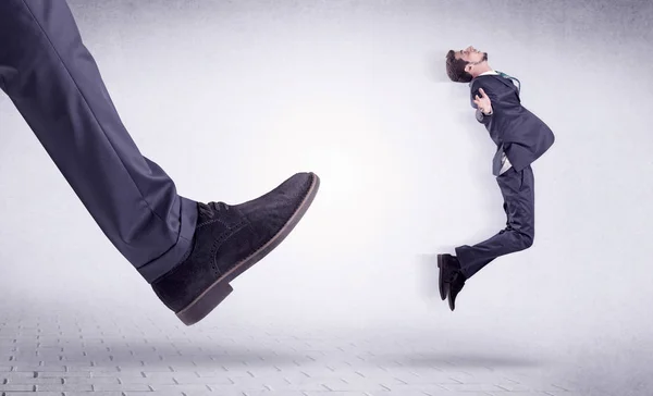 Young worker kicked out by big foot — Stock Photo, Image