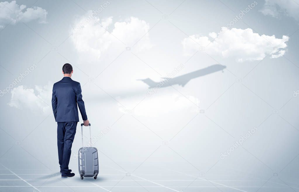 Businessman with luggage  look to an airplane