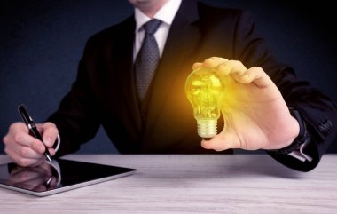 parlak sarı ampul tutan takım elbiseli adam