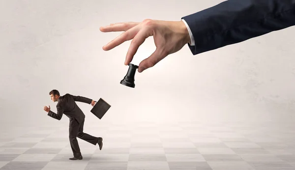 Small businessman running away from big hand with chessman concept — Stock Photo, Image