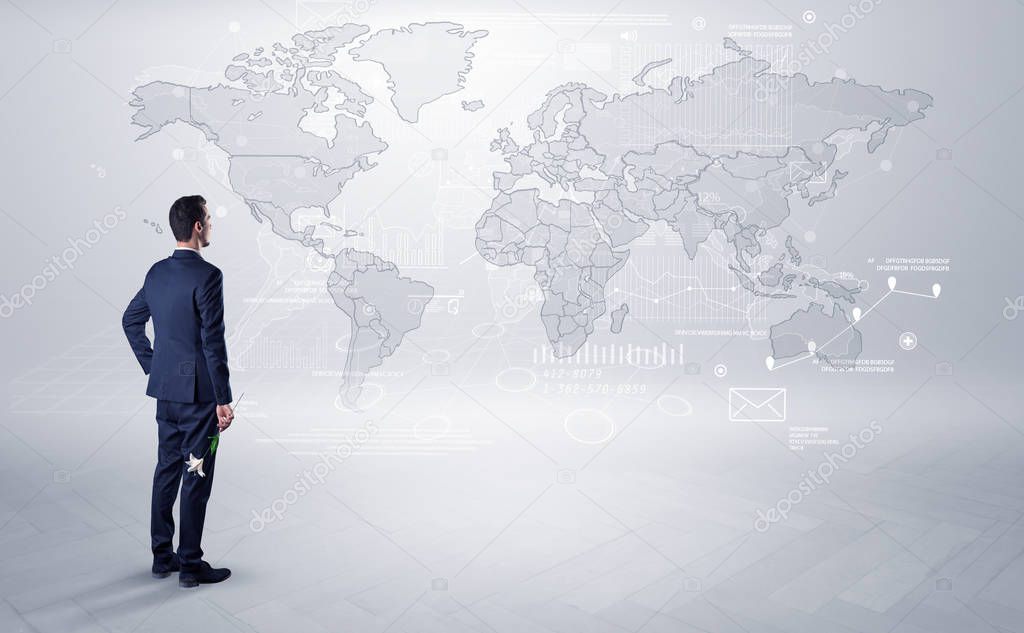 Businessman standing with his back and looking at a worldwide map with objects in his hand