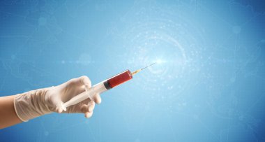 Kadın doktor elinde şırınga tutuyor.