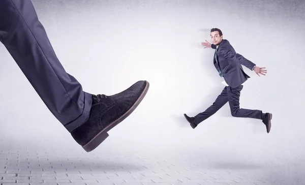 Young worker kicked out by big foot — Stock Photo, Image