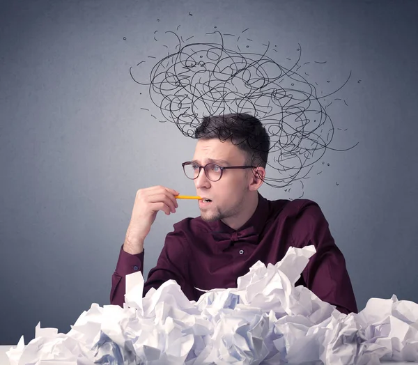 Genç işadamı buruşuk kağıt karalamalar ile başının üzerinde oturuyor.