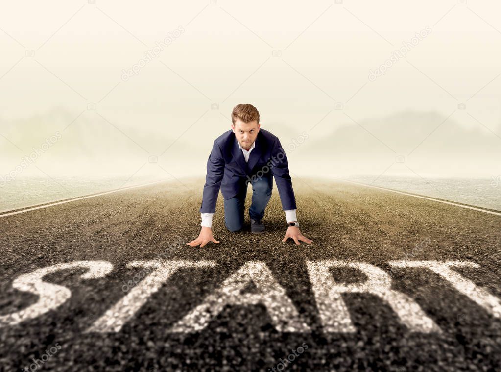 Young determined businessman kneeling at a start line 