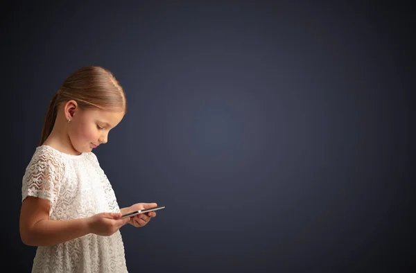 Nettes kleines Mädchen mit Tablet mit dunklem Hintergrund — Stockfoto