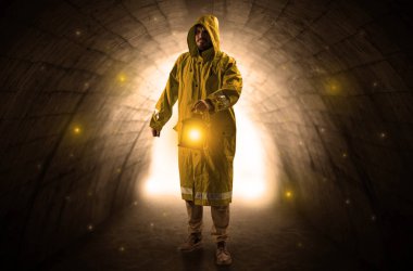 Karanlık bir tünelde fenerle yürüyen adam