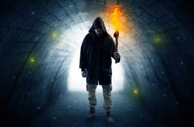 Man walking with burning flambeau in a dark tunnel clipart