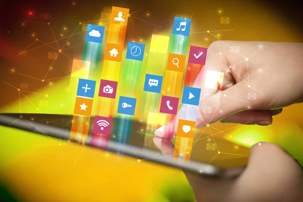 Main en utilisant une tablette avec des icônes d'application volant autour — Photo