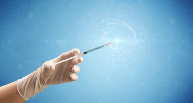 Kadın doktor elinde şırınga tutuyor.