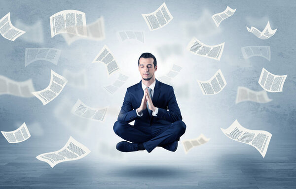 Businessman meditating with flying paper concept