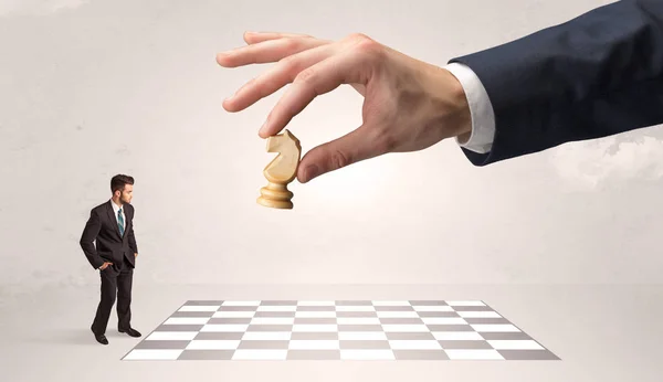 Pequeño hombre de negocios jugando al ajedrez con un gran concepto de mano —  Fotos de Stock