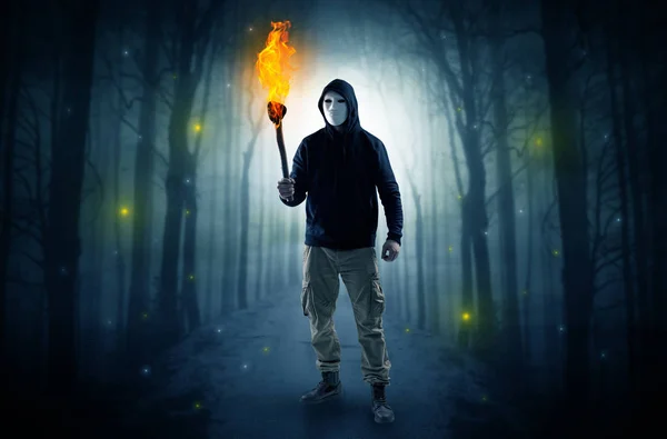 Ο άνθρωπος που βγαίνει από το σκοτεινό δάσος με καύση flambeau στην έννοια του χέρι — Φωτογραφία Αρχείου