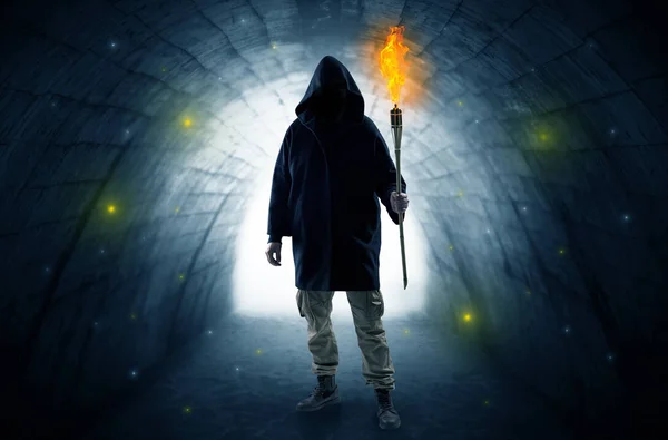 Man walking with burning flambeau in a dark tunnel — Stock Photo, Image