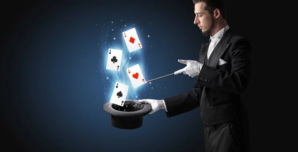 Magician making trick with wand and playing cards — Stock Photo, Image