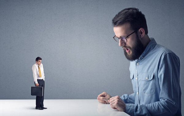 Young businessman fighting with miniature businessman