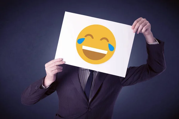 Бізнесмен тримає папір зі сміховинним емоційок — стокове фото