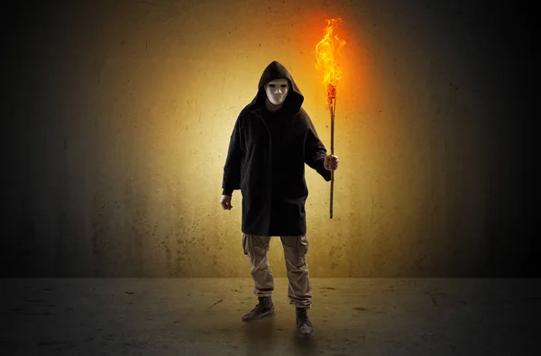 Man walking in an empty space with burning flambeau