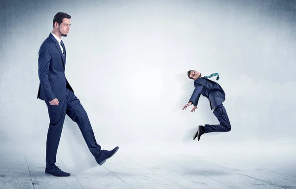 Big businessman kicking small businessman — Stock Photo, Image