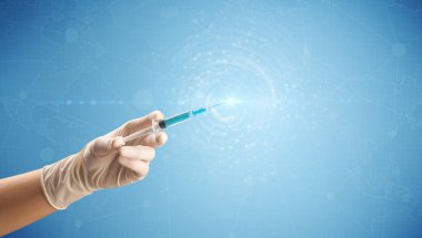 Kadın doktor elinde şırınga tutuyor.