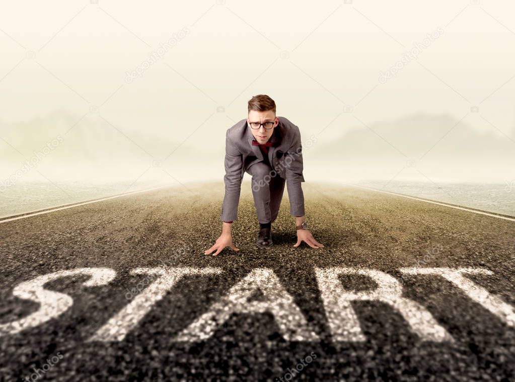 Young determined businessman kneeling at a start line 