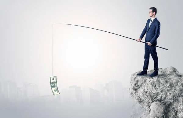 Businessman fishing dollar from a rock — Stock Photo, Image