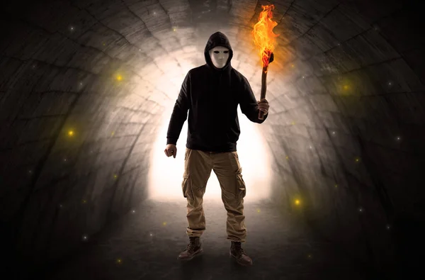 Hombre caminando con flambeau ardiente en un túnel oscuro — Foto de Stock