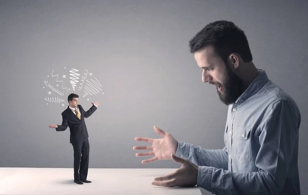 Young businessman fighting with miniature businessman — Stock Photo, Image