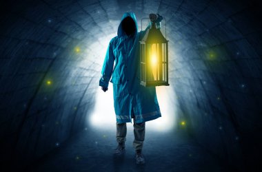 Man walking with lantern in a dark tunnel clipart