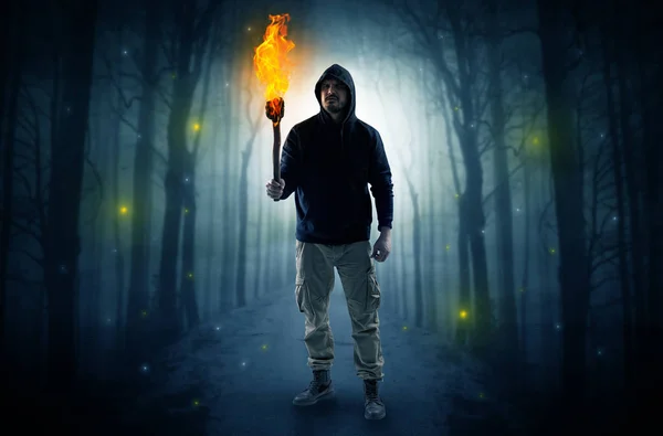 Man coming from dark forest with burning flambeau in his hand concept — Stock Photo, Image