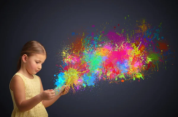 Menina segurando comprimido com respingo colorido ao redor — Fotografia de Stock