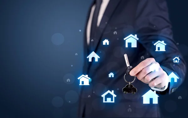 Businessman holding keys with houses around — Stock Photo, Image