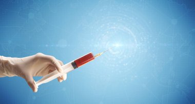 Kadın doktor elinde şırınga tutuyor.