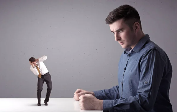 Giovane uomo d'affari che lotta con uomo d'affari in miniatura — Foto Stock