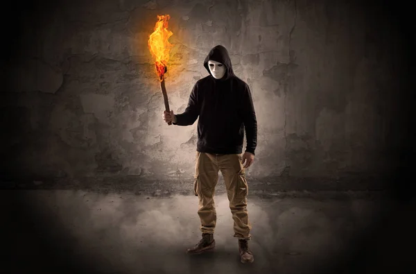 Wayfarer with burning torch in front of crumbly wall concept — Stock Photo, Image