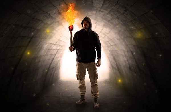 Man walking with burning flambeau in a dark tunnel — Stock Photo, Image