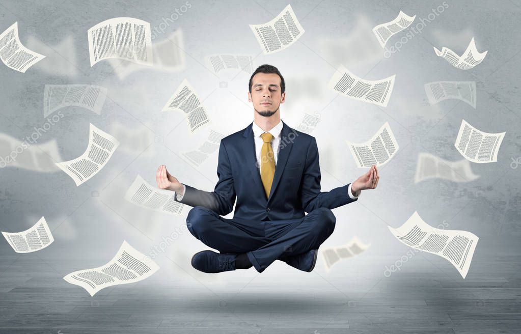 Businessman meditating with flying paper concept