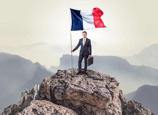 Homme d'affaires sur le dessus d'un drapeau d'attente de roche — Photo