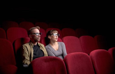 Genç çift kırmızı sinemada oturuyor