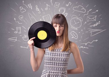 Onun arkasında karışık karalamalar ile gri bir arka plan üzerinde vinil kaydı tutan genç bayan