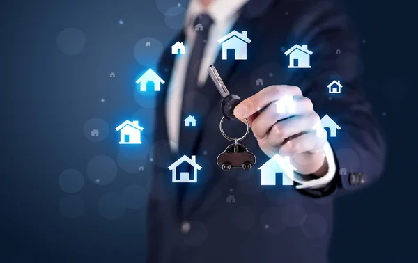 Businessman holding keys with houses around — Stock Photo, Image
